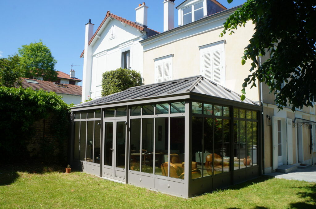 Véranda haut de gamme en aluminium gris adossée à une maison de ville